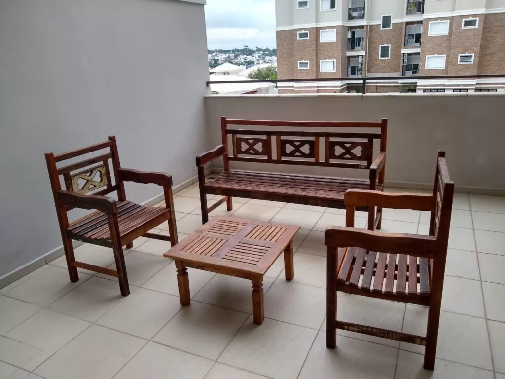 Mesa de madeira rústica com bancos em terraço de apartamento.