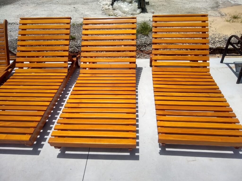 Três espreguiçadeiras para piscina feitas de madeira de garapa.